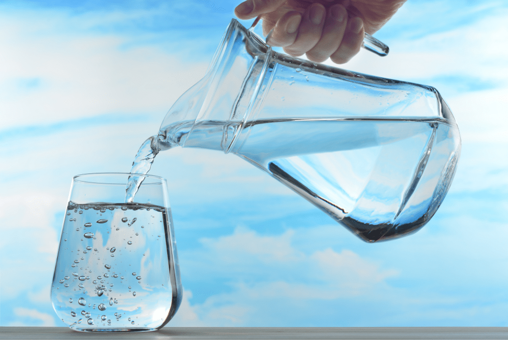 person serving a glass of water with a pitcher