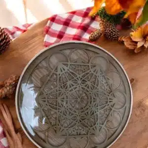 Plateau de dynamisation StructFood en céramique avec motif géométrique, posé sur une table en bois avec décoration naturelle.