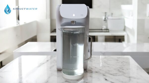 Mini Water reverse osmosis fountain from StructWater with filled carafe, set on a marble countertop.