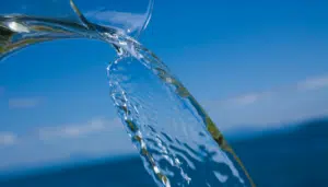 Eau en mouvement versée dans un décor naturel avec ciel bleu.