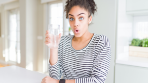 Jeune femme surprise devant son verre d'eau agressive